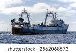 Fishing vessel lifts trawl tackle off the southern tip of Africa. Large fishing trawler is fishing for fish and seafood in ocean. 