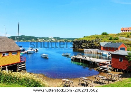 Fishing village, harbor scene; fish drying on stages, boats moored to the pier, Trinity, Newfoundland Labrador.