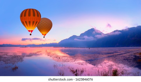 Fishing village on the coast of the Lake Batur on the background amazing sunset with hot air balloon - Bali island, Indonesia