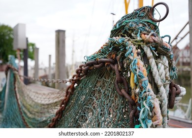 Fishingnet with a rusty chain und colourful ropes at the fishing port.