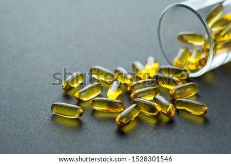 Fishoil capsules out of the small glass on black background with copy space.Selective focus