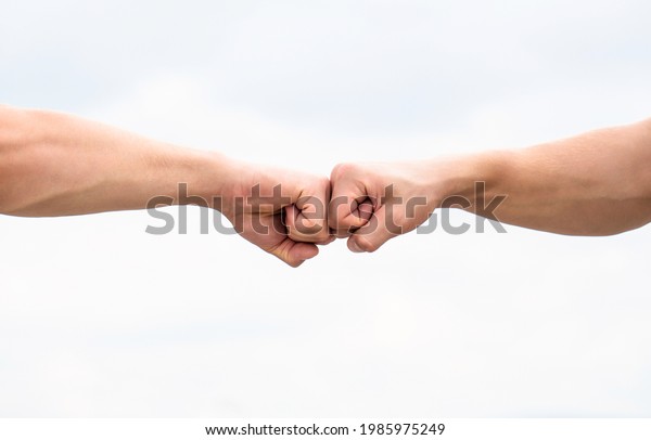 Fist Bump. Clash of two fists. Concept of\
confrontation, competition. Gesture of giving respect or approval.\
Teamwork and friendship. Partnership concept. Man giving fist bump.\
Bumping fists together