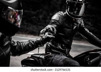 fist bump greeting of two motorbike riders in leather clothes and helmets  - Shutterstock ID 2129766131