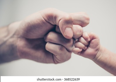 Fist of Dad and Newborn Baby
