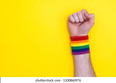 Fist Hand With Gay Pride Rainbow Flag Wristband On A Yellow Background