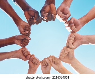 Fist hands, circle and diversity support human rights people, protest group and freedom of racism on blue sky background. Below solidarity, partnership and motivation of goals, trust or world justice - Shutterstock ID 2216364531