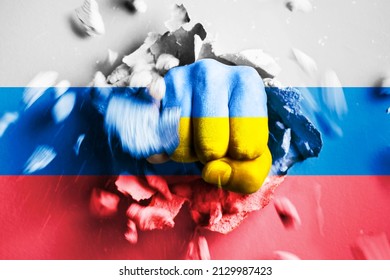 A fist punches through a concrete wall with the colors of the Ukrainian and russian flags. The concept of Ukraine crushes Russia army and won in war