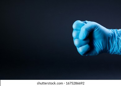 Fist Of Right Man Hand In A Blue Medical Glove On A Black Background