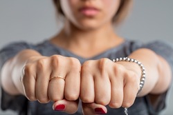 Fists Clenched Together Of A Young Woman. Is This A Sleight Of Hand And Hiding Something, Or Is It A Threatening Gesture? In Any Case, She Is Wearing A Ring And A Bracelet, And Her Nails Are Painted R