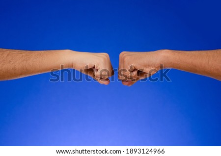 Fists of two people clashing, on a blue background.