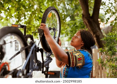 Fit and active female cyclist fastening bike tire safely for outside cycling. Dedicated african american woman performing bike maintenance skillfully fixing bicycle wheel with essential work tool. - Powered by Shutterstock