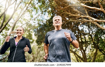 Fit, Active And Healthy Mature Couple Jogging, Running And Enjoying Their Fitness Lifestyle Outside In Nature During Summer. Happy, Smiling And Free Senior Man And Sporty Woman Exercise Together