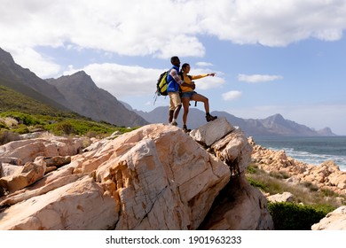 Fit afrcan american couple wearing backpacks hiking embracing on the coast. healthy lifestyle, exercising in nature. - Powered by Shutterstock