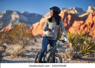 Fit African American Woman With Bike Stopping To Use Smartphone At Red Rock Canyon Park