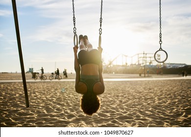 fit african american woman flipping upside down on gymnastic rings at exercise park - Powered by Shutterstock