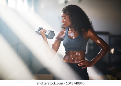 Fit African American Woman Lifting Iron In Home Gym