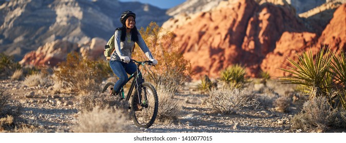 fit african american woman riding bicycle offroad in red rock canyon park panorama - Powered by Shutterstock