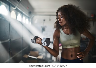 Fit African American Woman Working Out By Lifting Weights In Home Gym