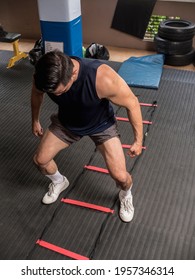 A Fit Asian Guy Doing An HIIT Workout With An Agility Ladder At An Indoor Gym. Feet Outside The Square. Fitness Routine.