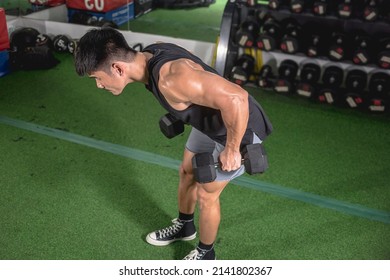 A fit asian man does bent-over dumbbell rows. Weight and resistance training at the gym. - Powered by Shutterstock