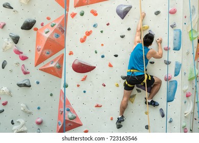 Fit Asian Man Rock Climbing Indoors At The Gym