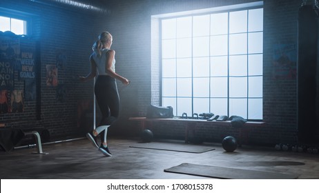 Fit Athletic Blond Woman Exercises With Jumping Rope In A Loft Style Industrial Gym. She Does Her Intense Fitness Training Program. Facility Has Motivational Posters On The Wall.