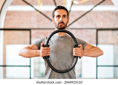 Fit Athletic Man Using A Pilates Magic Circle Or Ring To Strengthen His Muscles And Align His Posture In A Gym In A Close Up Upper Body View