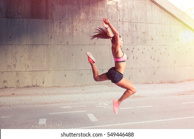 Fit Athletic Woman Runner Performing A Big Leap Outdoors