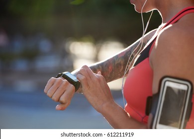 Fit Athletic Woman With Tattoos Tracking Her Run Exercise Progress With Wearable Technology Watch Mobile Smartphone In Urban City