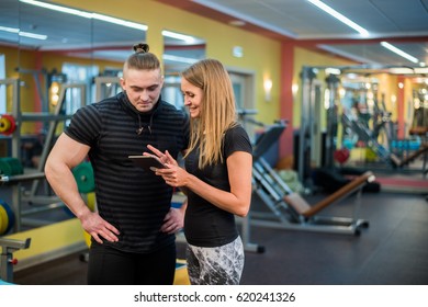 Fit attractive young couple at a gym looking at a tablet-pc as they monitor their progress and fitness - Powered by Shutterstock