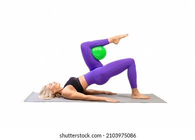 Fit beautiful woman practice shoulder bridge drill with one leg up and a small rubber ball under her bent knee, isolated on white.
