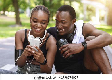 Fit Black Couple Using Smartphone After Training Outdoors, Checking Physical Activity Measurements In Fitness Mobile App. Closeup - Powered by Shutterstock