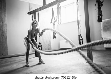 Fit Blonde Beautiful Woman With Battle Ropes Exercise In The Fitness Gym. Young Female Wearing Sportswear. 