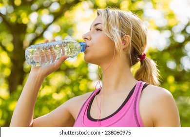 Fit blonde drinking from her water bottle on a sunny day