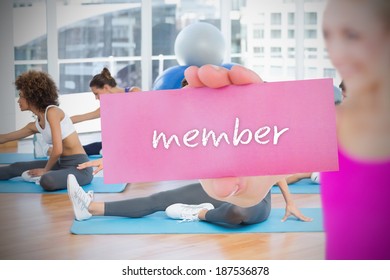 Fit Blonde Holding Card Saying Member Against Yoga Class In Gym