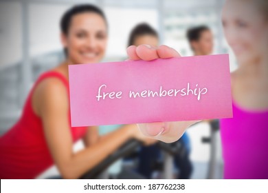 Fit Blonde Holding Card Saying Free Membership Against Bike Class In Gym