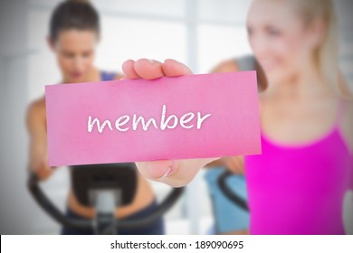 Fit Blonde Holding Card Saying Member Against Spinning Class In Gym