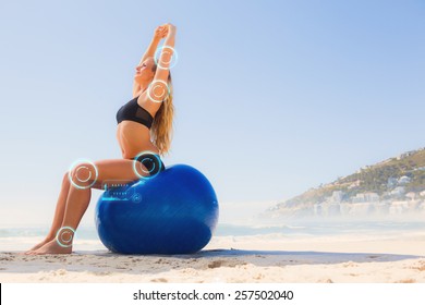 Fit Blonde Sitting On Exercise Ball At The Beach Against Fitness Interface