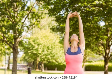 Fit brown hair stretching her arms in the park