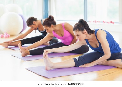 Fit class stretching legs on mats at yoga class in fitness studio - Powered by Shutterstock