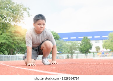 Fit And Confident Fat Boy In Starting Position Ready For Running. Kid Athlete About To Start A Sprint Looking Forword. Exercise Concept