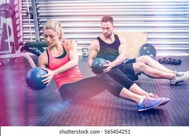 Fit Couple Doing Abdominal Ball Exercise At Gym