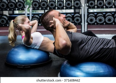 Fit couple doing sit ups on bosu ball at gym - Powered by Shutterstock