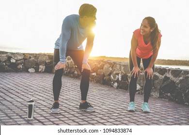 Fit couple taking a rest after fast running workout - Joggers training outdoor at sunset together - Main focus on girl face - Fitness, sport, wellness, workout, gym and healthy lifestyle concept - Powered by Shutterstock