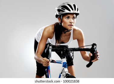 Fit cyclist woman on road racing bicycle isolated in studio with dramatic lighting. Riding bike as if in a race. - Powered by Shutterstock