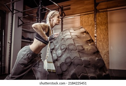 Fit female athlete flipping huge tire. Woman lifts a heavy wheel. Muscular young woman doing functional training exercise at gym. - Powered by Shutterstock