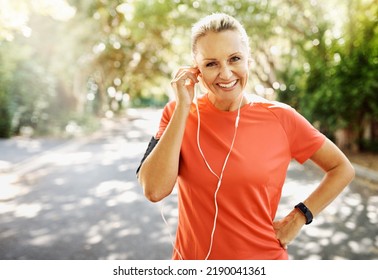 Fit female athlete going for morning run, adjusting earphones, listening to music. Happy, healthy sports woman smiling, about to do cardio wellness exercise or take endurance training workout break. - Powered by Shutterstock