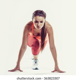 Fit Female Athlete Ready To Run Over Grey Background. Female Fitness Model Preparing For A Sprint.