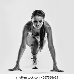 Fit Female Athlete Ready To Run Over Grey Background. Female Fitness Model Preparing For A Sprint.