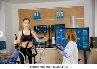 Fit Female Doing Endurance Test In The Lab. Doctor Makes Notes In The Tablet